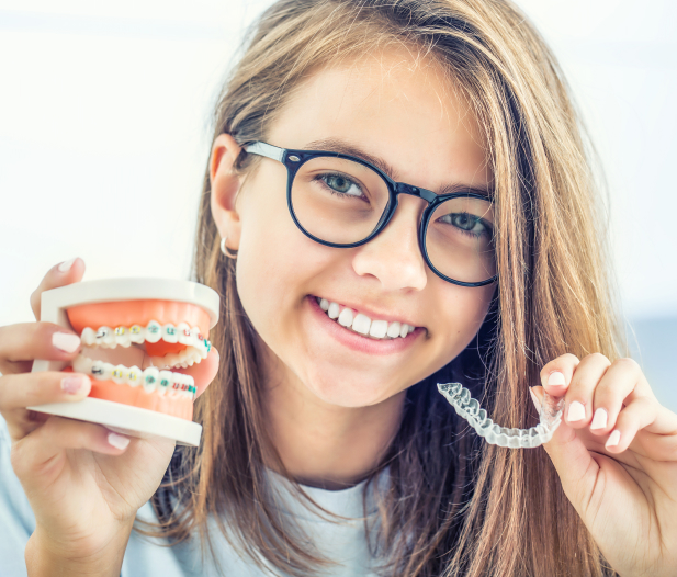 Girl smiling holding Invisalign and Denture prototype